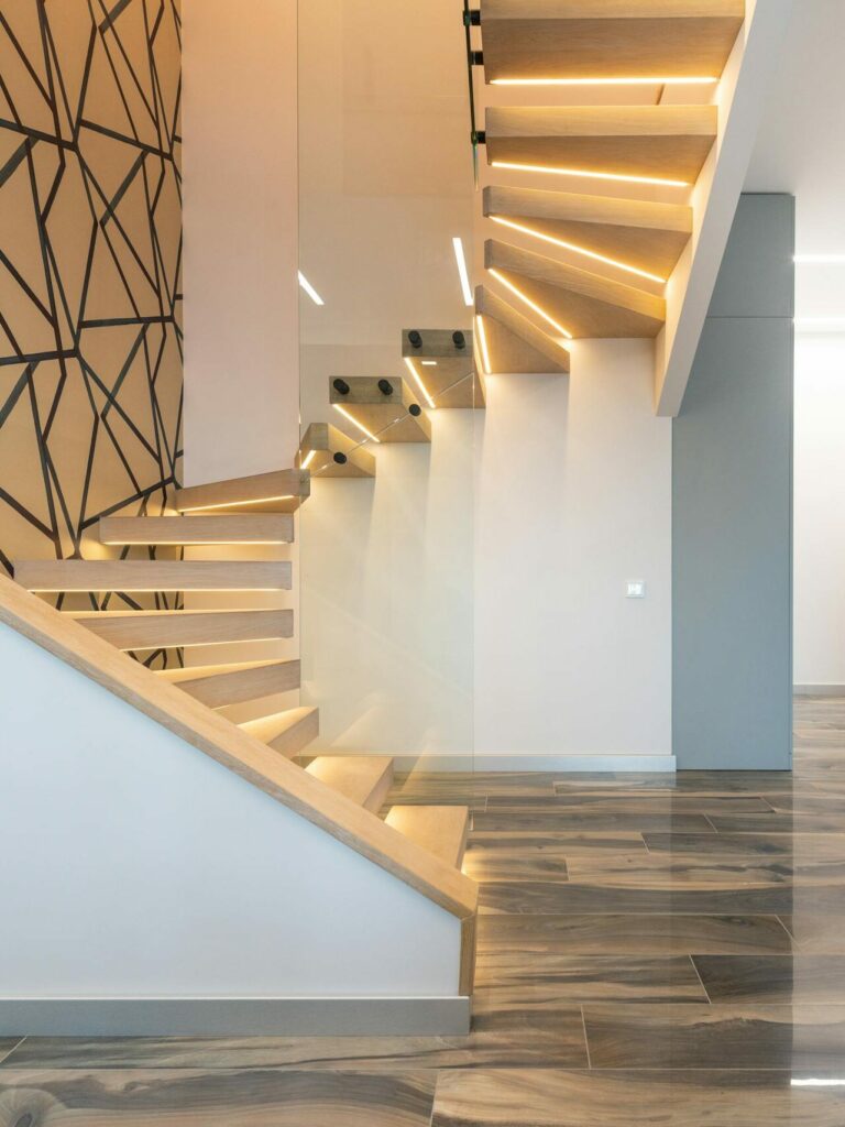 Contemporary hall interior with door against curved staircase and wall with geometric ornament in light house